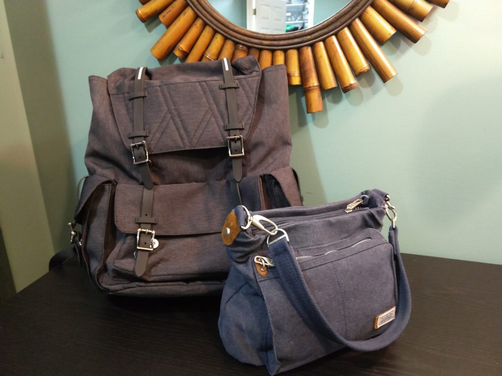 An indigo-colored purse and a large, gray backpack, both empty and ready for packing