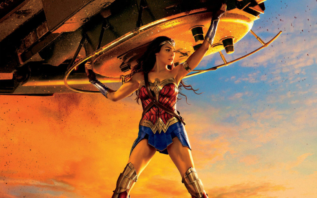 Wonder Woman carrying a very large object, with heroic sunset lighting behind her.