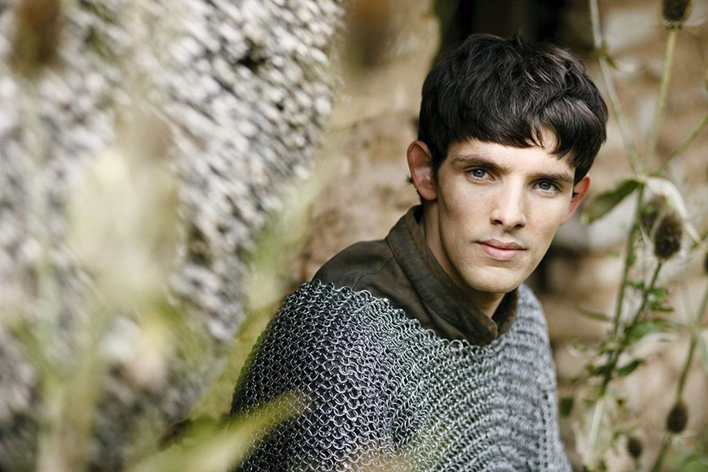 Colin Morgan as the character of Merlin: A teen boy with short brown hair, wearing Medieval chain mail, gazes steadily into the camera.